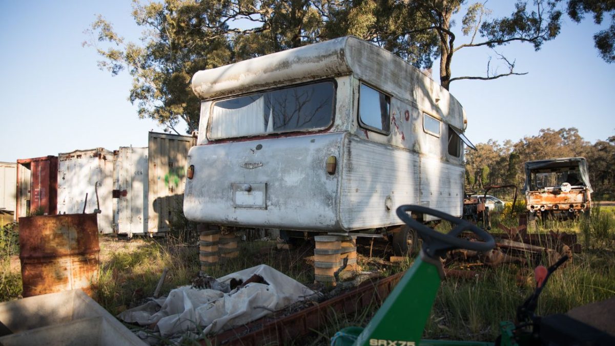 old disused abandoned caravan on a farm at sunset